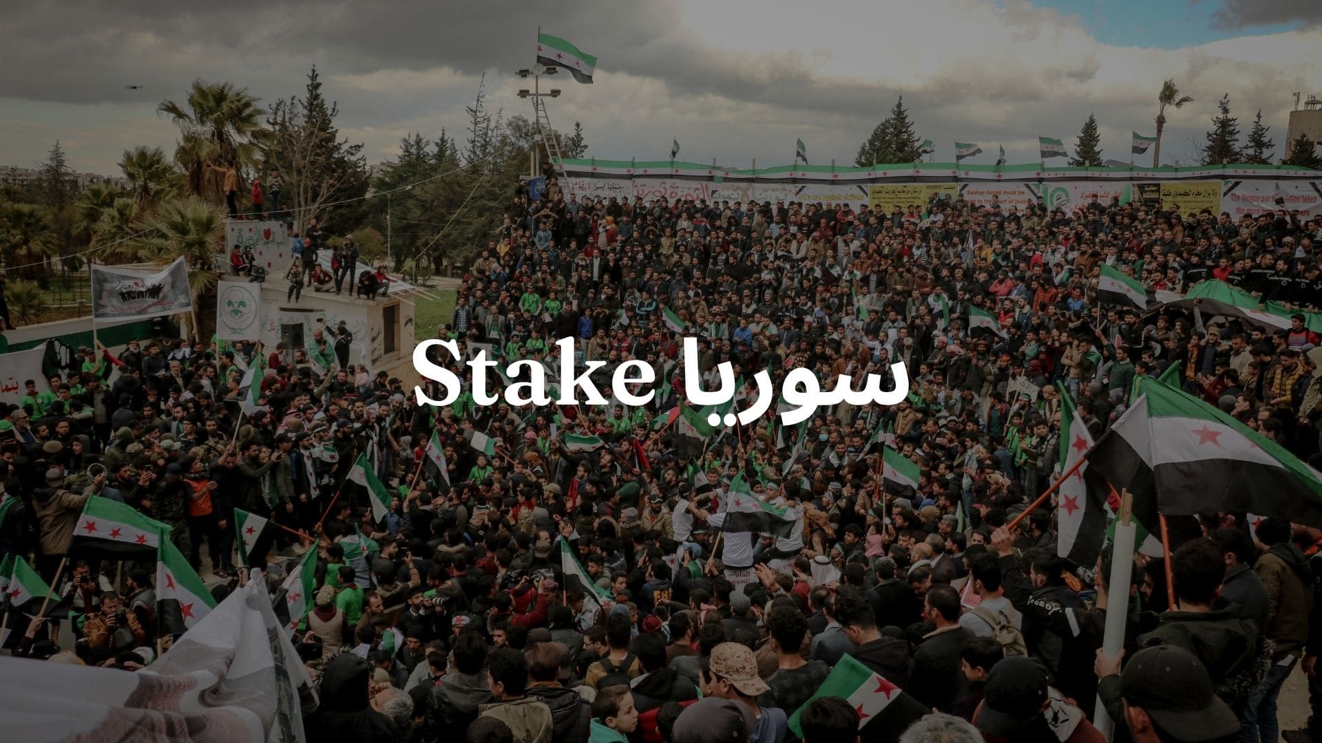 Stake سوريا: صورة لمدينة سورية مع أشخاص يرفعون علم البلاد