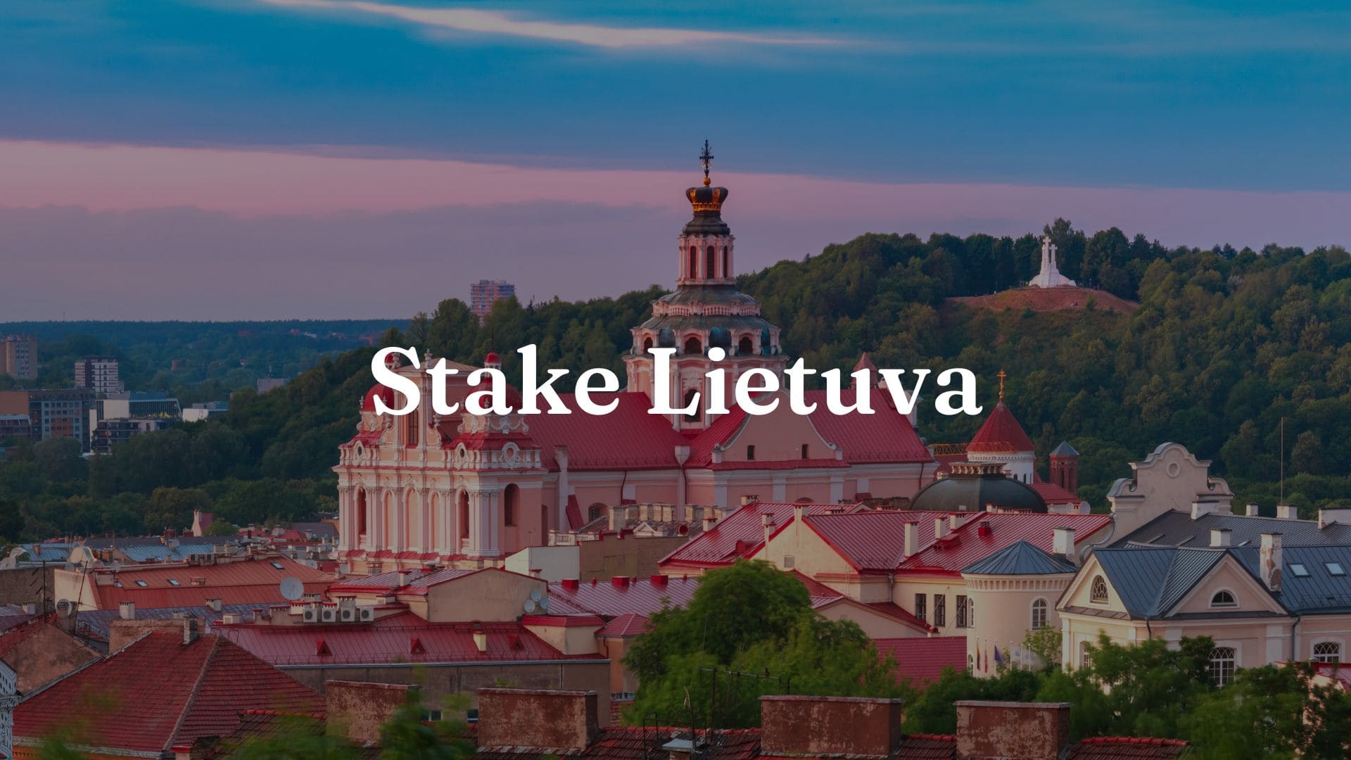 Stake Lietuva: Vaizdas iš labai gražaus miesto Lietuvoje su rožiniais namais, kuriame matomas užrašas „Stake Lietuva“.
