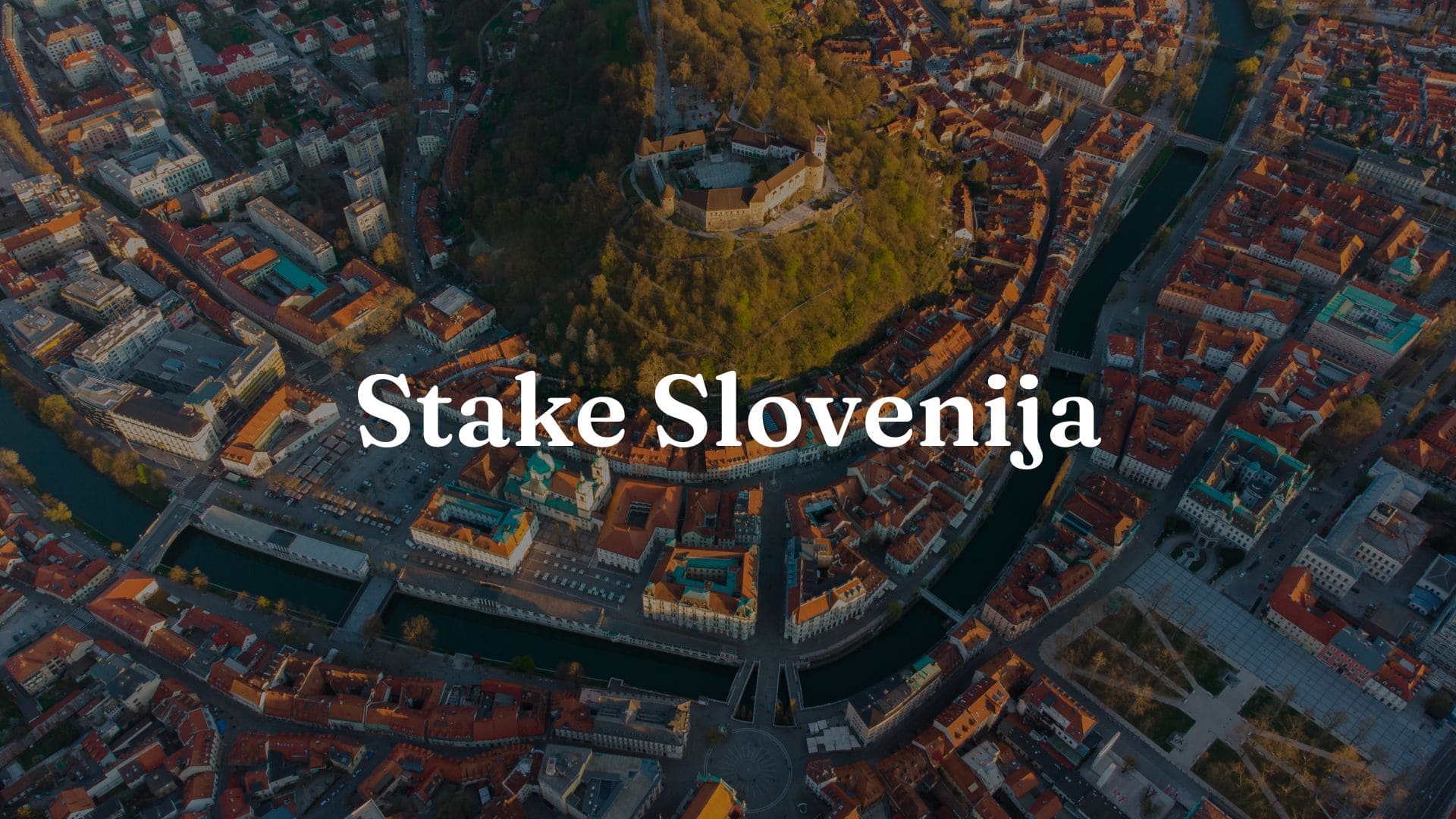 Stake Slovenija: Slika mesta v Sloveniji z majhno goro, na kateri stoji grad. Na sliki so tudi vidne besede Stake Slovenija.